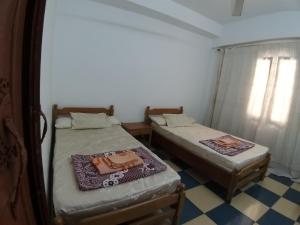2 Betten in einem kleinen Zimmer mit Fenster in der Unterkunft Vacation Apartments in a Private Villa with Private Beach Access in Alexandria