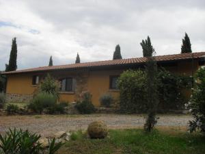 una casa amarilla con árboles y un cementerio en Agriturismo Podere Mulinaccio, en Ribolla