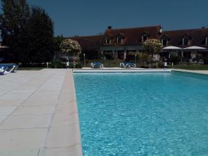een zwembad met blauw water voor een huis bij Chambres d'hôtes Au Clos de Beaulieu in Bossée