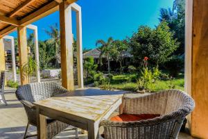 Une table et des chaises en bois sont disponibles sur la terrasse. dans l'établissement Biba Beach Village, à Gili Air
