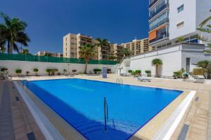 une grande piscine bleue avec des bâtiments en arrière-plan dans l'établissement LA ESTRELLA 1A020, à Los Cristianos