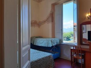 sypialnia z oknem, łóżkiem i biurkiem w obiekcie Hotel Italia w mieście Marina di Massa