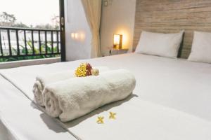 a white bed with a blanket and flowers on it at Sultans Of Swell Uluwatu Bali in Uluwatu