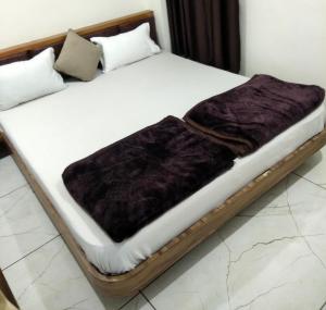 a wooden bed with a purple blanket on it at Hotel Milan in Ahmedabad