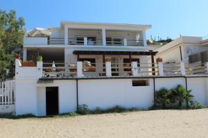 une maison blanche sur la plage à côté du sable dans l'établissement Home Holiday Punta Piccola, à Porto Empedocle