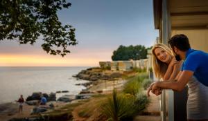 Un uomo e una donna fuori da una casa che guardano l'oceano di Amber Sea Luxury Village Mobile Homes a Novigrad Istria