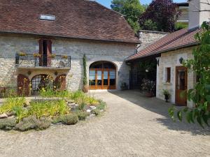 a stone house with a patio and a courtyard at L'écurie in Saint-Germain-lès-Arlay