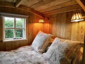 a bedroom with a bed with two pillows and a window at The Wayside Shepherd Hut in Beaulieu