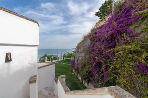 a wall covered in purple flowers next to the ocean at La Casa E Il Mare, Private Bay Hotel in Mattinata