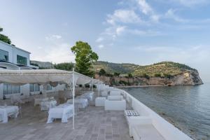 a restaurant with white tables and chairs next to the water at La Casa E Il Mare, Private Bay Hotel in Mattinata