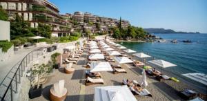 a beach with a row of white umbrellas and the water at LUKA in Budva
