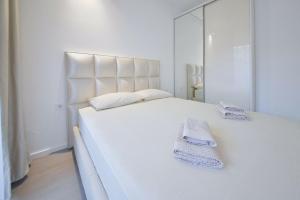 a white bedroom with a large white bed with mirrors at LUKA in Budva