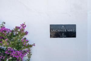 a sign on a white wall next to flowers at La Casa E Il Mare, Private Bay Hotel in Mattinata