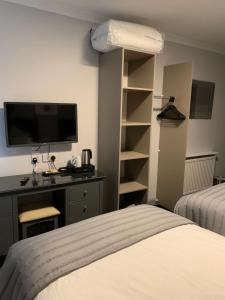 a bedroom with a bed and a desk and a tv at The Royal Hotel in Stranraer