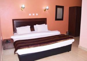 a bedroom with a large bed with orange walls at Residency Hotels Ogidi in Ogidi