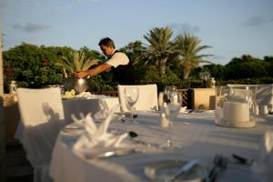 un uomo in piedi davanti a un tavolo con una tovaglia bianca di Avanti Hotel a Paphos