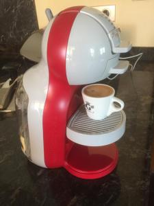 - une machine à café avec une tasse sur une étagère dans l'établissement Les Bruyeres, à La Bresse