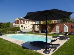 um guarda-sol e cadeiras junto a uma piscina em Casa Vacanze Villa Cerine em Altopascio