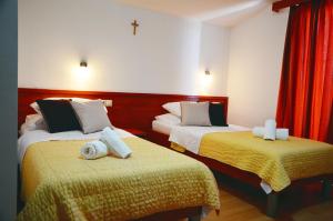 a hotel room with two beds and a cross on the wall at Hotel Quattro Medjugorje in Međugorje