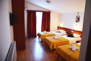 Habitación de hotel con 3 camas con sábanas de color naranja en Hotel Quattro Medjugorje, en Međugorje