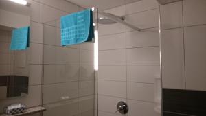 a bathroom with a shower with blue towels at Pension ILMHOF in Bad Berka
