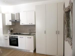 敘拉古的住宿－Nesh House，白色的厨房配有白色橱柜和水槽