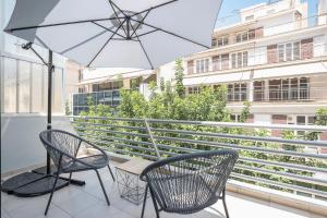 雅典的住宿－Athens Lights，阳台的天井配有2把椅子和1把遮阳伞