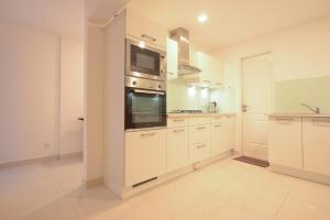 a large kitchen with white cabinets and a microwave at De Saram Residencies in Colombo