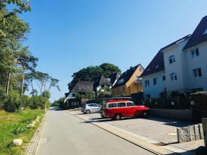 a red car parked in a parking lot next to houses at Familie-Anker-Kiefernweg-4-H in Hohwacht