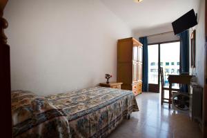 a bedroom with a bed and a tv and a window at Hostal Sa Rota in Santa Eularia des Riu
