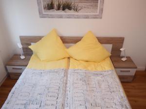 łóżko z dwoma żółtymi poduszkami na górze w obiekcie Seestern w mieście Hohwacht