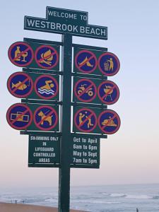 una señal para una playa con señales en ella en Westbrook Cabanas 1st, en Westbrook