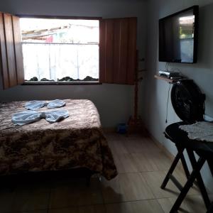 um quarto com uma cama, uma televisão e uma janela em Pousada Olinda em Pirenópolis