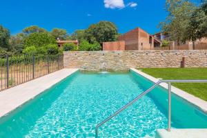 a swimming pool with a fountain in a yard at Flateli Diana in Sant Jordi Desvalls