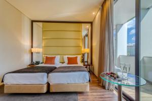 リスボンにあるツーリム アベニュー リベルダデ ホテルのベッドとガラスのテーブルが備わるホテルルームです。