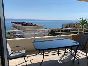 d'une table bleue et de chaises sur un balcon donnant sur l'océan. dans l'établissement Superbe appartement 3 étoiles Ajaccio début Sanguinaires, à Ajaccio