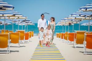 una passeggiata di famiglia sulla spiaggia con sedie e ombrelloni di Hotel Parco Dei Principi a Giulianova