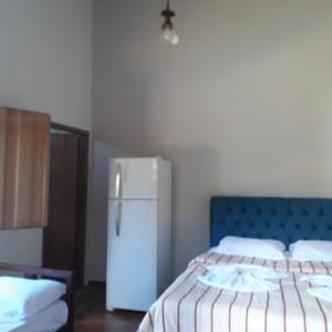 um quarto com uma cama e um frigorífico branco em Pousada Olinda em Pirenópolis