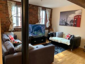 a living room with two couches and a flat screen tv at 2 Bed Duplex Penthouse Apartment by Mathew Street Sleeps 6 in Liverpool