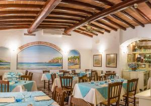 a restaurant with blue tables and chairs and a large window at Hotel Elba in Marina di Campo