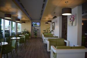un comedor con mesas, sillas verdes y registrador en BluePoint Hotel en Kakavijë