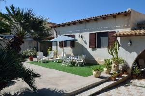 een huis met een patio met stoelen en een parasol bij Villa Silvana in Mazara del Vallo