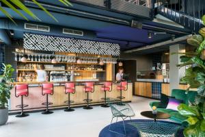 a bar with red chairs and a counter at The Social Hub Eindhoven in Eindhoven