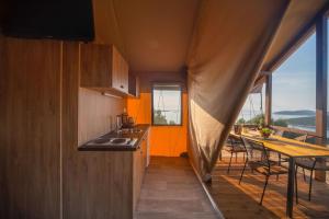a kitchen with an orange wall and a table with chairs at Glamping Tents and Mobile Homes Trasorka in Veli Lošinj