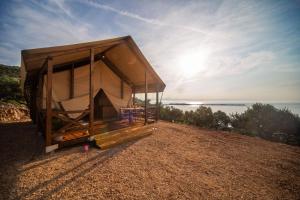 a wooden bench sitting on top of a sandy beach at Glamping Tents and Mobile Homes Trasorka in Veli Lošinj