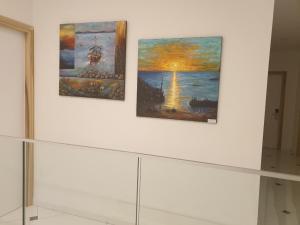 three paintings on a white wall in a room at Hai Hotel in Larnaca