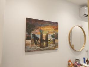 a painting hanging on a wall next to a mirror at Hai Hotel in Larnaca