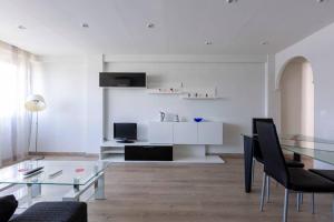 een witte woonkamer met een glazen tafel en stoelen bij Apartamentos La Vaguada Suites in Madrid