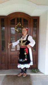 uma mulher vestida com roupas tradicionais em pé em frente a uma porta em Apartmani Nik Lux em Vrnjačka Banja