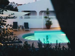 a swimming pool with two chairs and a house at Vivenda Brito in Carvoeiro